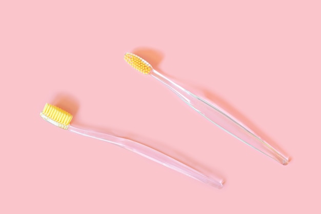 Toothbrushes with yellow bristles on a pink wall.