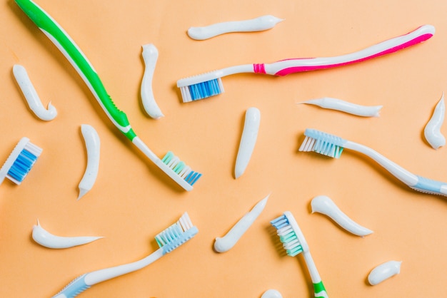 Toothpaste with different type of toothbrushes on colored background