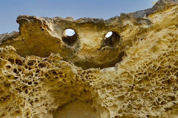 Top of the cliff in the form of a smiling face with eyes and a mouth Texture weathered limestone background The bottom of the ancient sea Abstract background