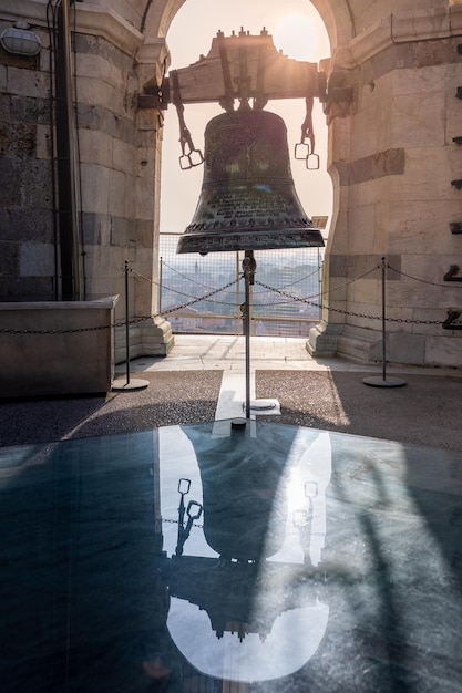 Top floor of Leaning Tower with big bell close up arch and marble walls in sunrise light Pisa Italy