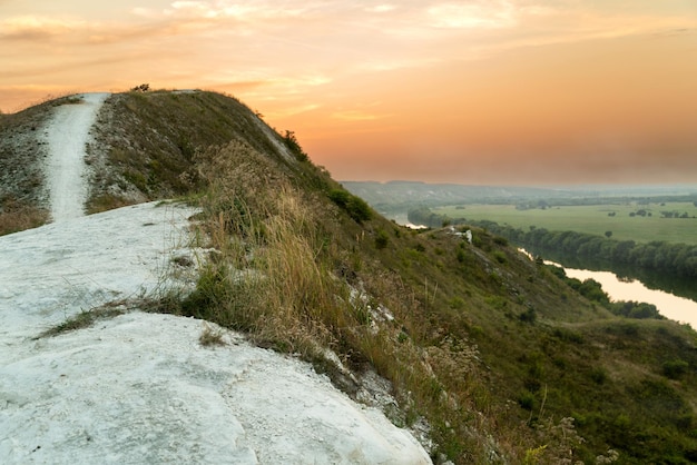 Top of hill under pink dramatic sky with feather clouds sunset landscape