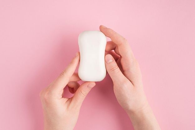 Top above overhead pov first person view photo of female hands holding soap isolated on pastel pink background with copyspace