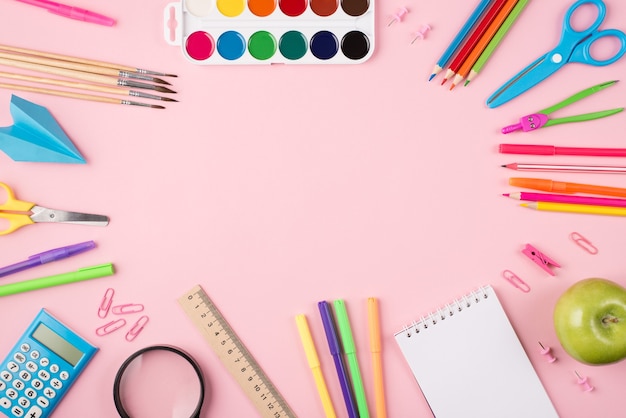 Top above overhead view photo of colorful stationery and apple isolated on pastel pink background with copyspace in the center