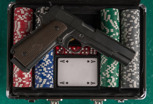 Top shot of a weapon on an open poker case on a green board