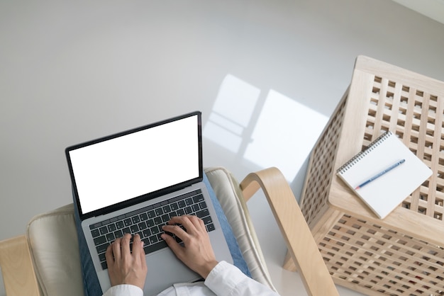 Top shot woman working on the reclining chair with laptop notebook computer at home.