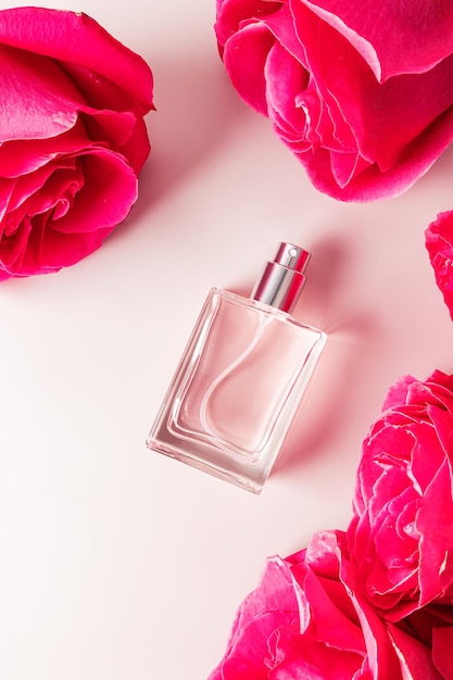 Top vertical view of a beautiful bottle of cosmetic spray among the heads of a garden rose The concept of a floral fragrance Product presentation