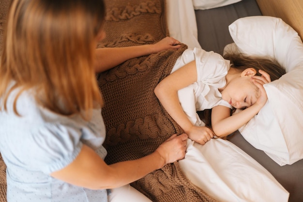 Top view of adorable sick little girl sleeping on bed in children room under blanket at home Concept of children health