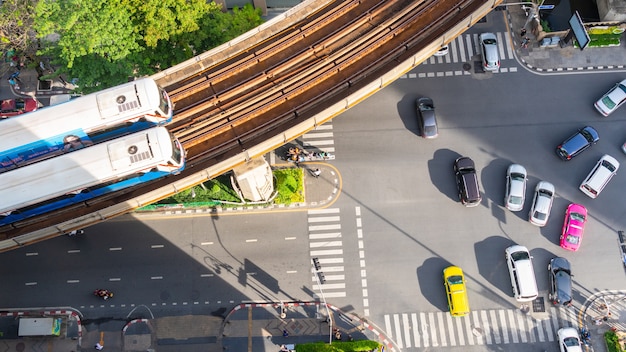 Top view aerial of a driving car on asphalt track and pedestrian crosswalk in traffic road.