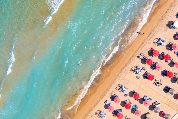 Top view aerial drone photo of Banana beach with beautiful turquoise water sea waves and red umbrellas Vacation travel background Ionian sea Zakynthos Island Greece