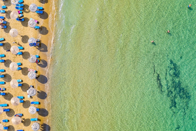 Top view aerial drone photo of beach with beautiful turquoise water sea waves and straw umbrellas Vacation travel background Ionian sea Corfu Island Greece