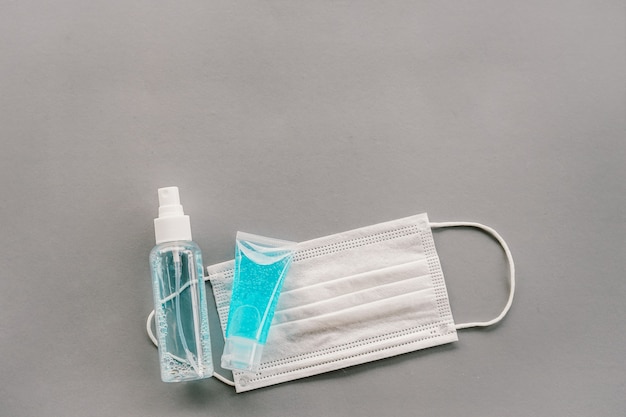 Top view of alcohol spray and gel on white surgical mask with grey