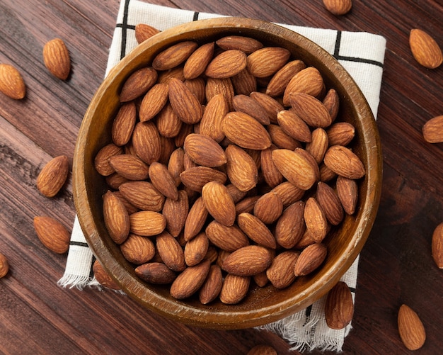 Top view of almonds in wooden bowl on the table, Flat lay, Healthy snack, Vegetarian food.