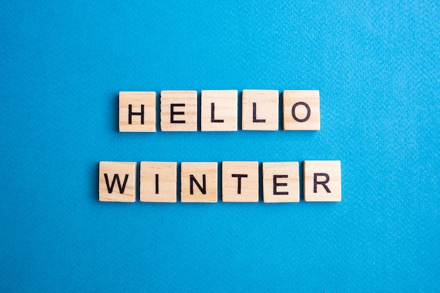 Top view of alphabet blocks with letters on a blue background. hello winter - lettering.