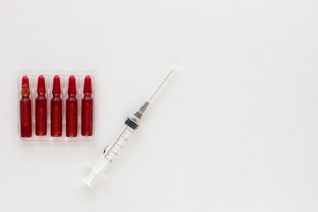 Top view of ampoules and syringe with vitamins group B for injection and copy space on the white background