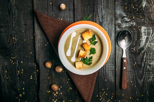 Photo top view on appetizing healthy puree soup on the napkin on the wooden table