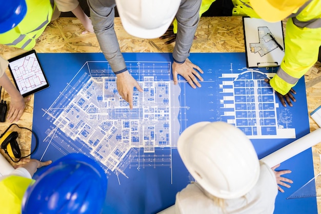 Top view of architects and engineers analyzing blueprint and project plant