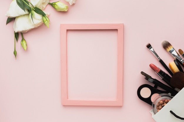 Top view arrangement with pink frame and make-up products