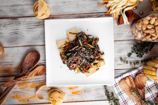 Top view on asian style noodles with beef and tofu cheese in square plate