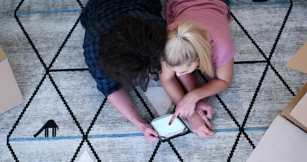 Top view of attractive young couple moving in, holding hands, while lying among cardboard boxes