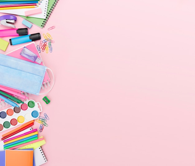 Top view of back to school essentials with medical mask and watercolor