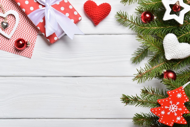 Top view of a background of fir branches, Christmas decorations and gifts on a white wooden table.New Year greeting card. A mock-up of a Christmas greeting. A place to copy. Flat lay.