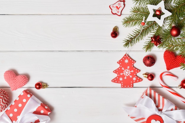 Top view of a background of fir branches, Christmas decorations and gifts on a white wooden table.New Year greeting card. A mock-up of a Christmas greeting. A place to copy. Flat lay.