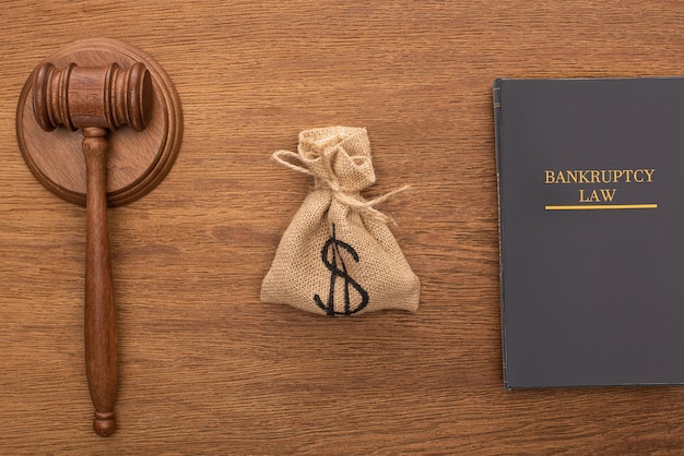 Top view of bankruptcy law book money bag and gavel on wooden background