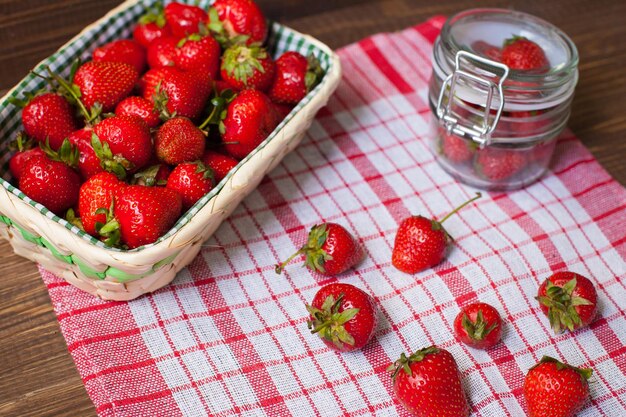 Top view of basket and glass bowl with fresh delisious strawberries on the tablecloth