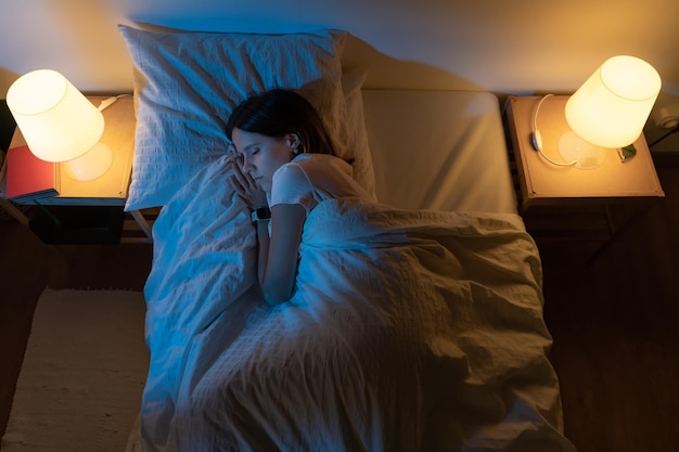 Top view of a beautiful girl sleeping cozily on a bed in her night room