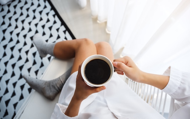 Top view  of a beautiful woman drinking hot coffee in bedroom at home in the morning