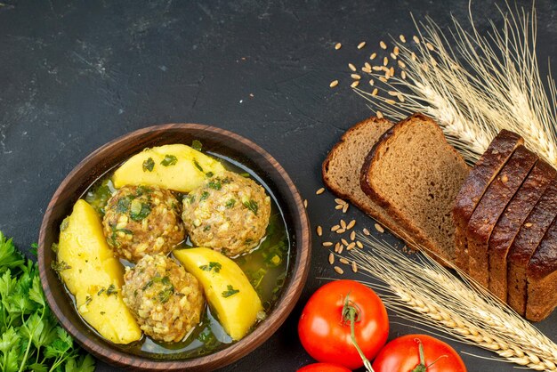 Top view of black bread slices delicious meatballs meal with potatoes green and tomatoes on black background