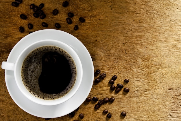 Top view, black coffee with coffee beans on wooden table background. Concept of drinking coffee and relaxing