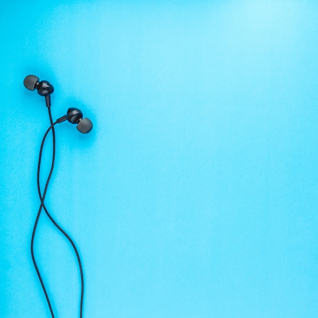 Top view of Black Earphones on Blue background