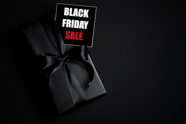 Top view of Black Friday Sale text with black gift box isolated on black background