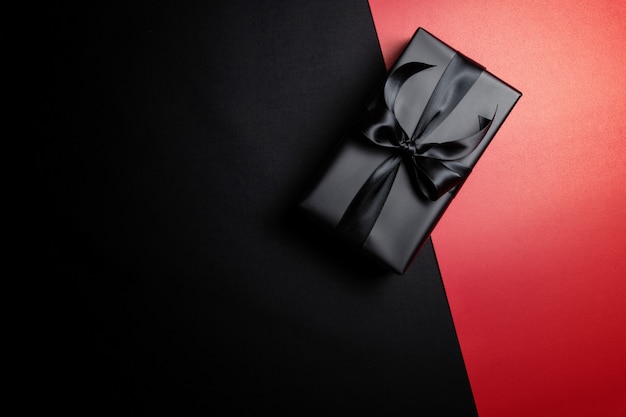 Top view of black gift box with black ribbons isolated on red and black