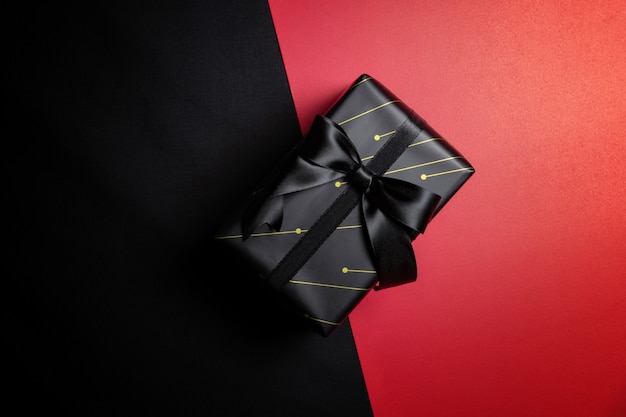 Top view of black gift box with black ribbons isolated on red and black