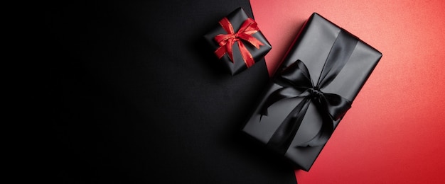 Top view of black gift box with red and black ribbons isolated on red and black