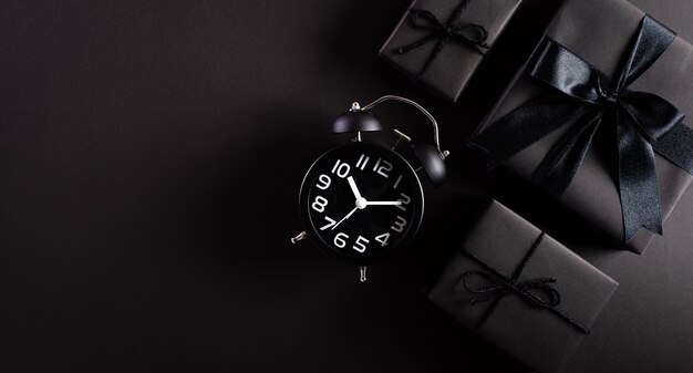 Top view of black gift boxes with alarm clock