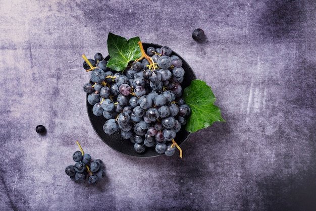 Top view of a black grapes with green leaves