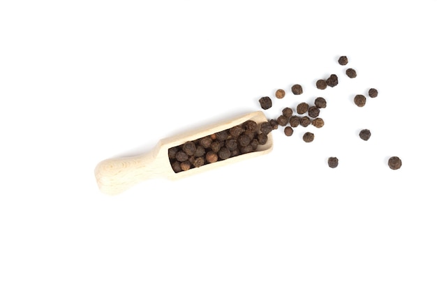 Top view of black pepper in a wooden scoop isolated on white background