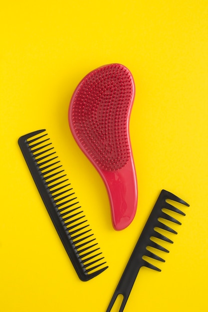 Top view of black and red hair combs on the yellow background