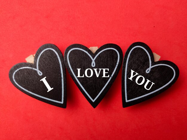 Photo top view black wooden love board with text i love you on a red background