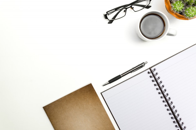 Top view blank notebook, pen and glasses on white desk