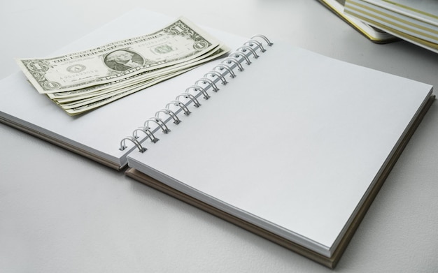 Top view of blank notebook with money dollar bills on desk