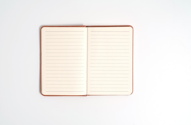 Top view blank orange leather diary on white desk