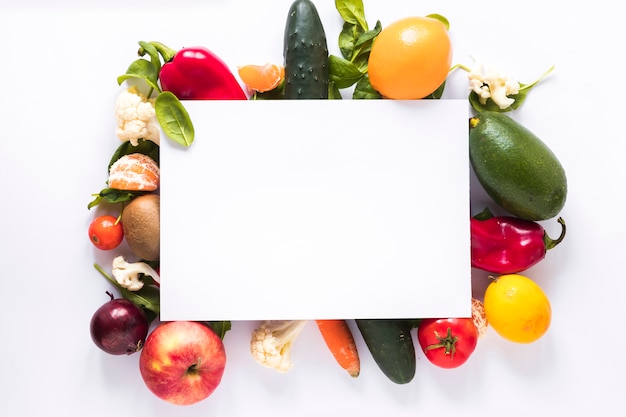 Photo top view of blank paper over fresh vegetables and fruits on white background