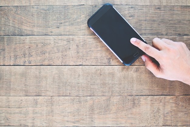 Top view of blank screen mobile phone with man's finger touching the screen