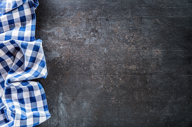 Top of view blue checkered tablecloth on dark concrete table.