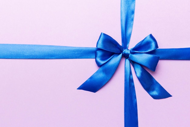 Top view of blue ribbon rolled and blue bow isolated on colored background Flat lay with copy space