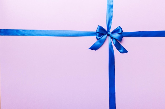 Top view of blue ribbon rolled and blue bow isolated on colored background Flat lay with copy space